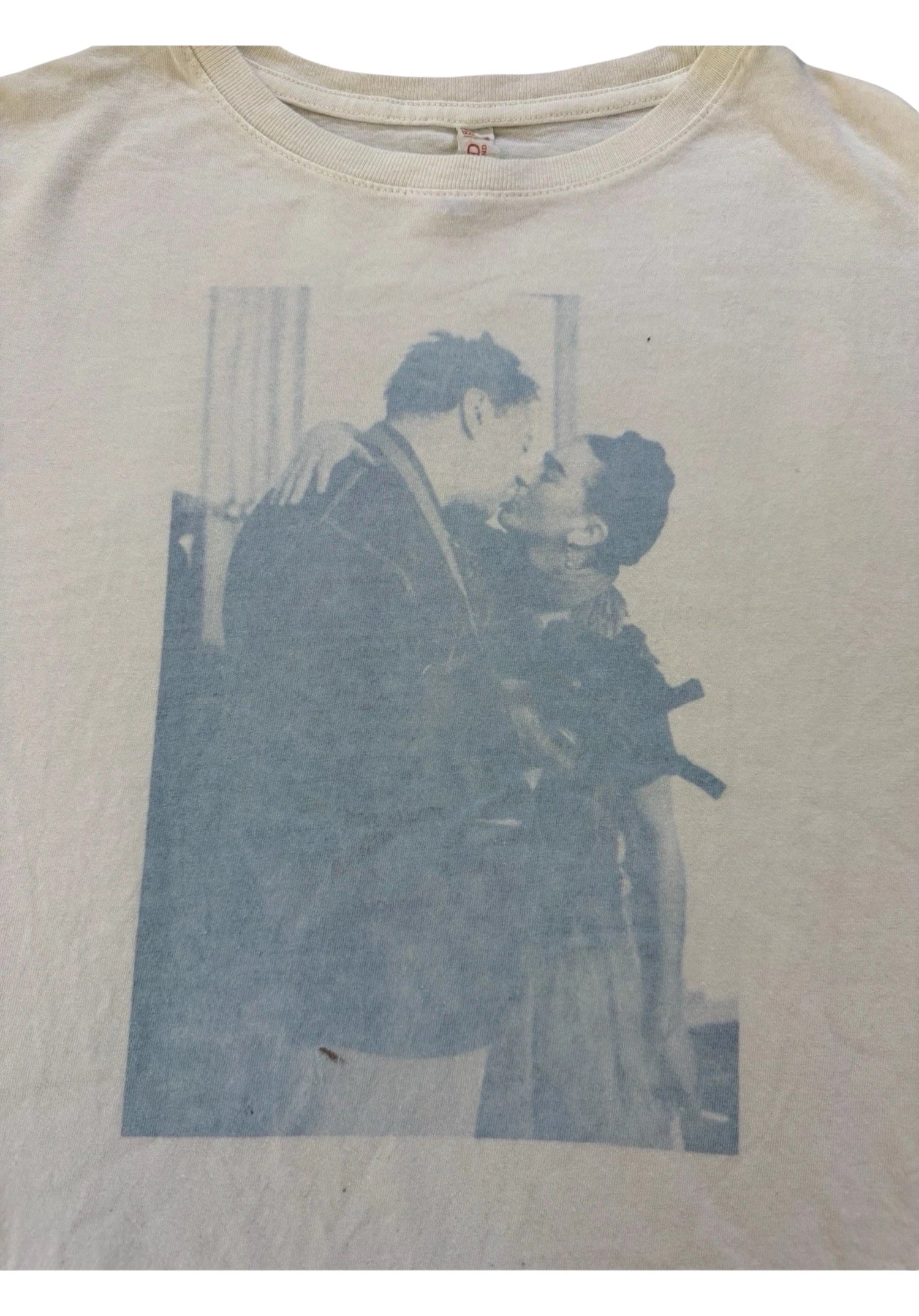 White T-shirt with a faded blue print of a couple embracing and about to kiss in a vintage photo style
