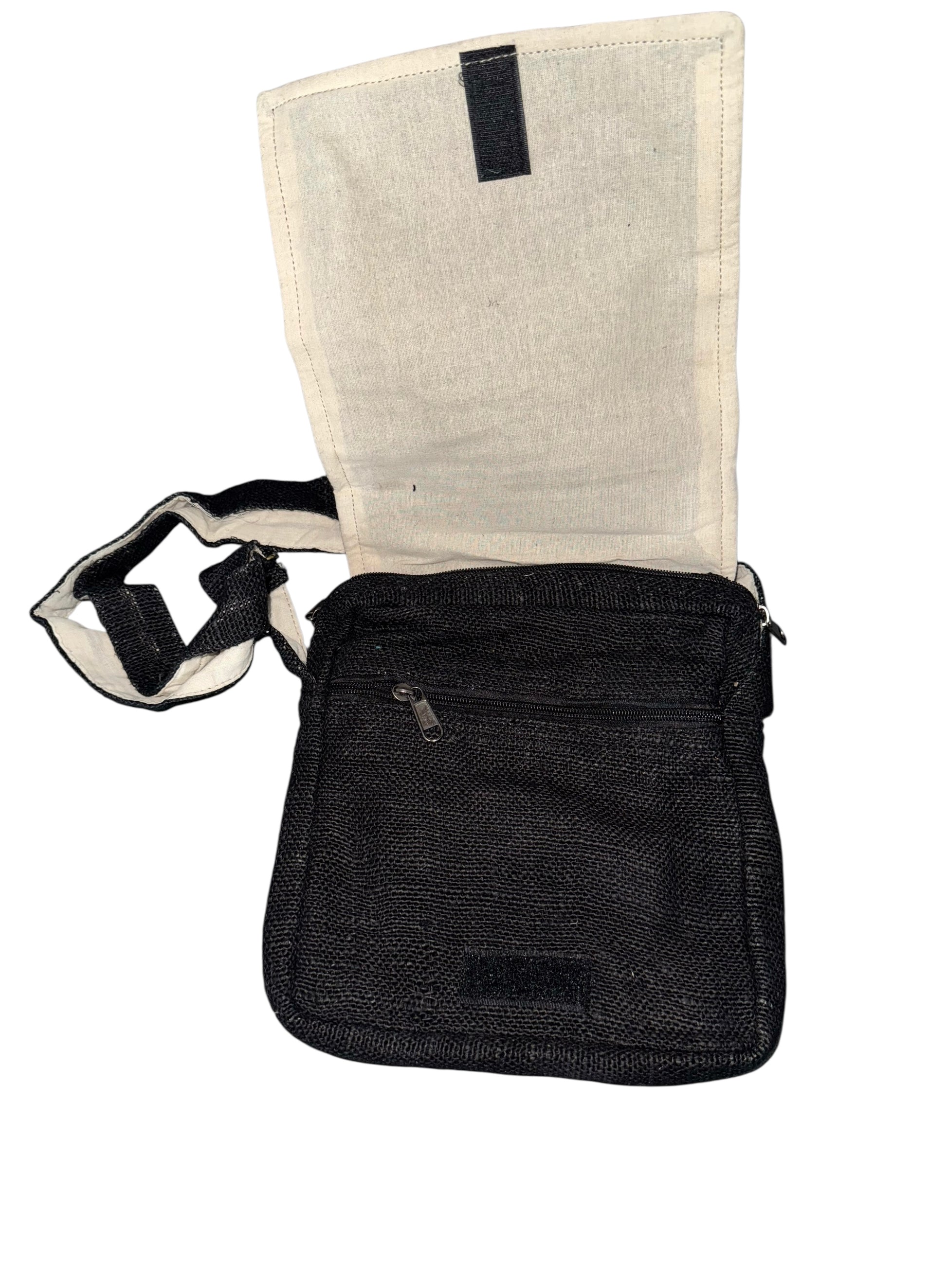 Black fabric crossbody bag with beige interior flap, zippered front pocket, and adjustable strap