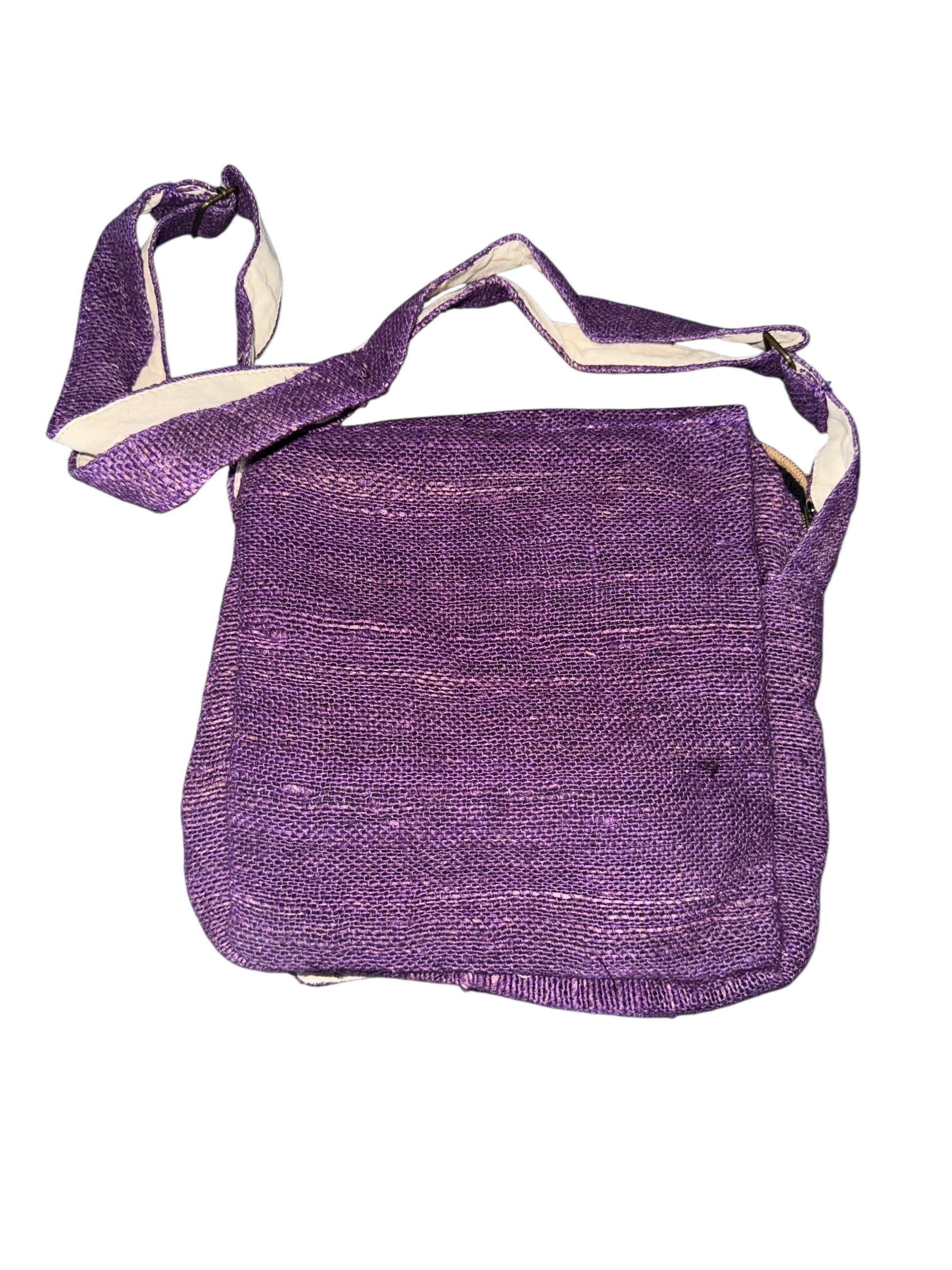 Purple woven crossbody bag with adjustable strap and flap closure on white background
