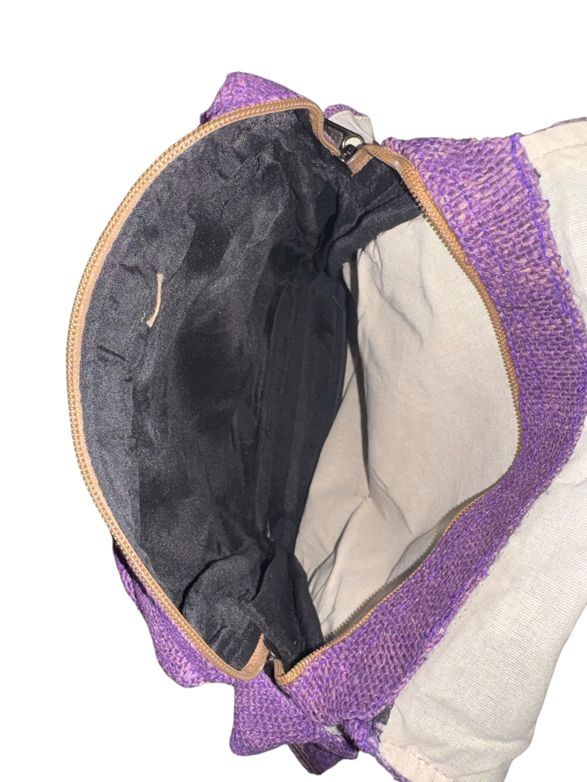 Open purple woven clutch bag showing black fabric interior with zipper closure